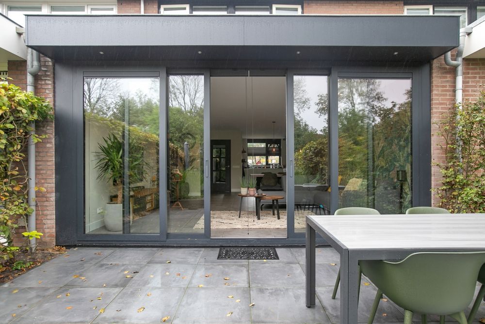 Afgeronde aanbouw met antraciet schuifpui en terras aan de achterzijde van de woning