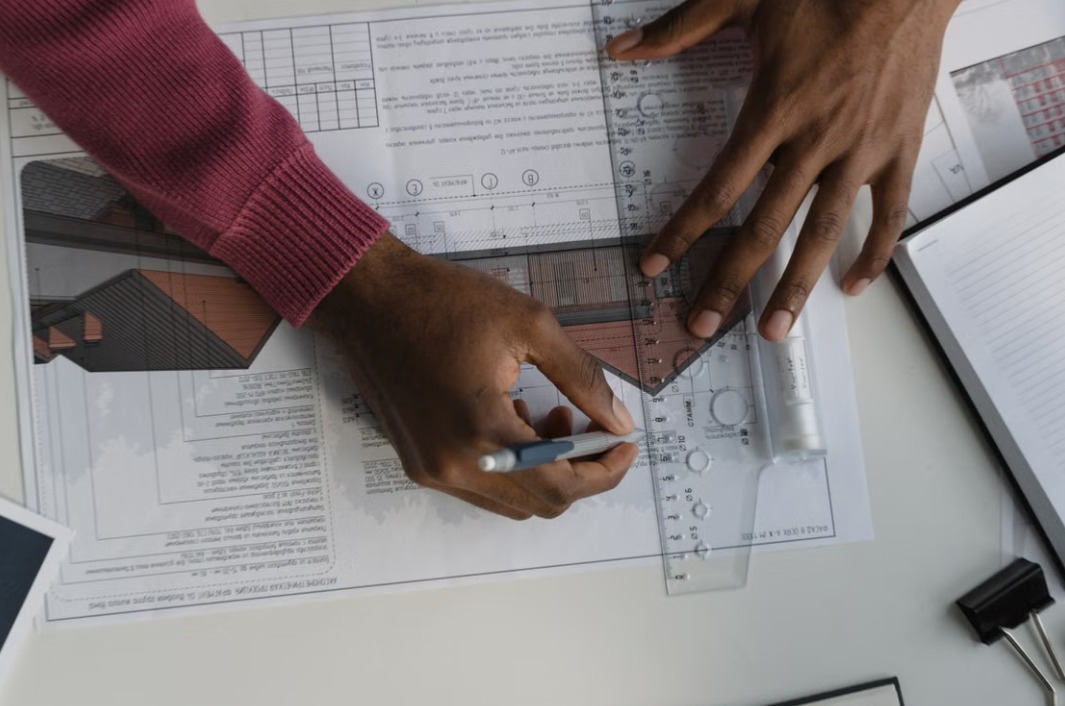 Vakman werkt met liniaal aan een bouwkundige tekening